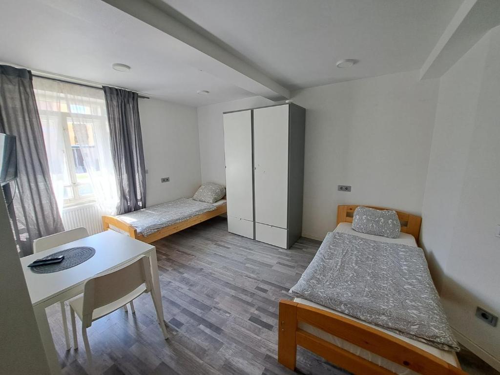 a room with two beds and a table and a desk at Monteurzimmer - Ferien Wohnungen Leipzig - Sandersdorf-Brehna in Deutsches Haus