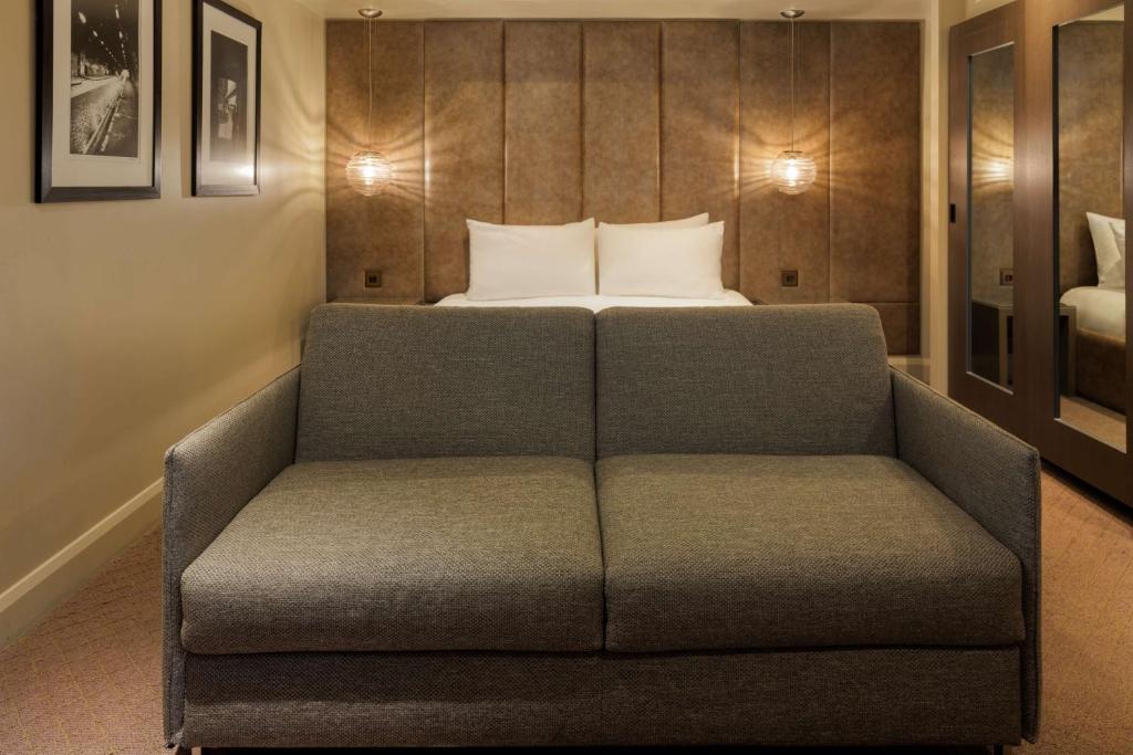 a couch in a room with a bed at Radisson Blu Hotel, London Bloomsbury in London