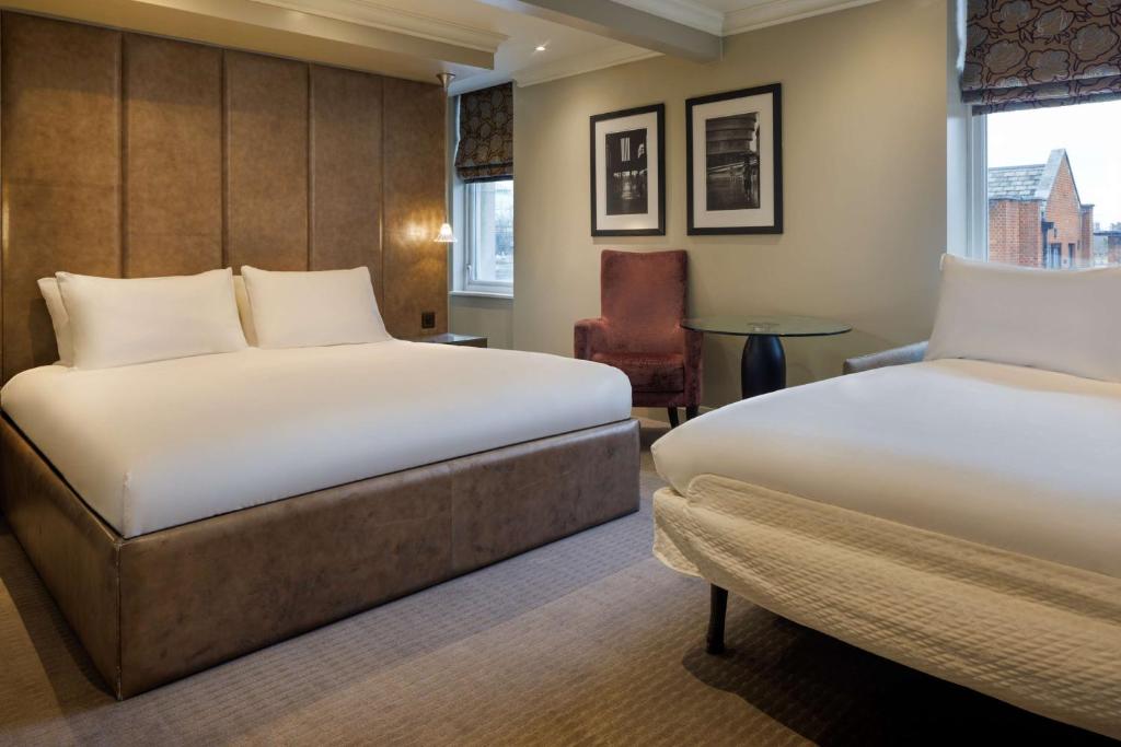 a hotel room with two beds and a chair at Radisson Blu Hotel, London Bloomsbury in London