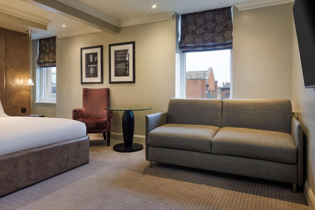 a bedroom with a bed and a couch and a chair at Radisson Blu Hotel, London Bloomsbury in London