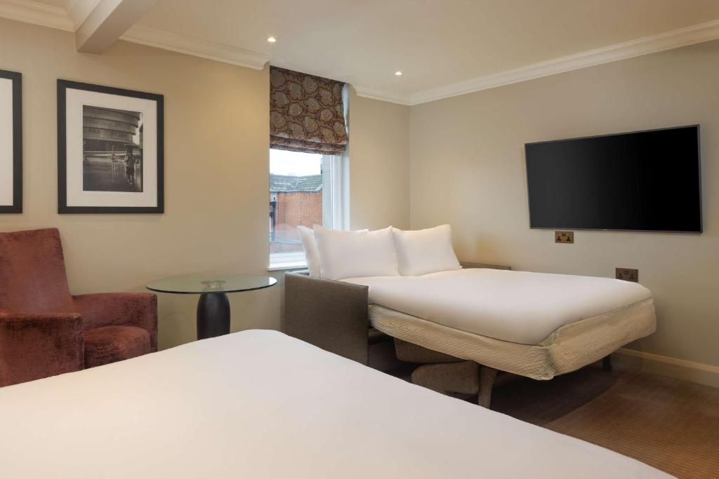 a hotel room with two beds and a flat screen tv at Radisson Blu Hotel, London Bloomsbury in London