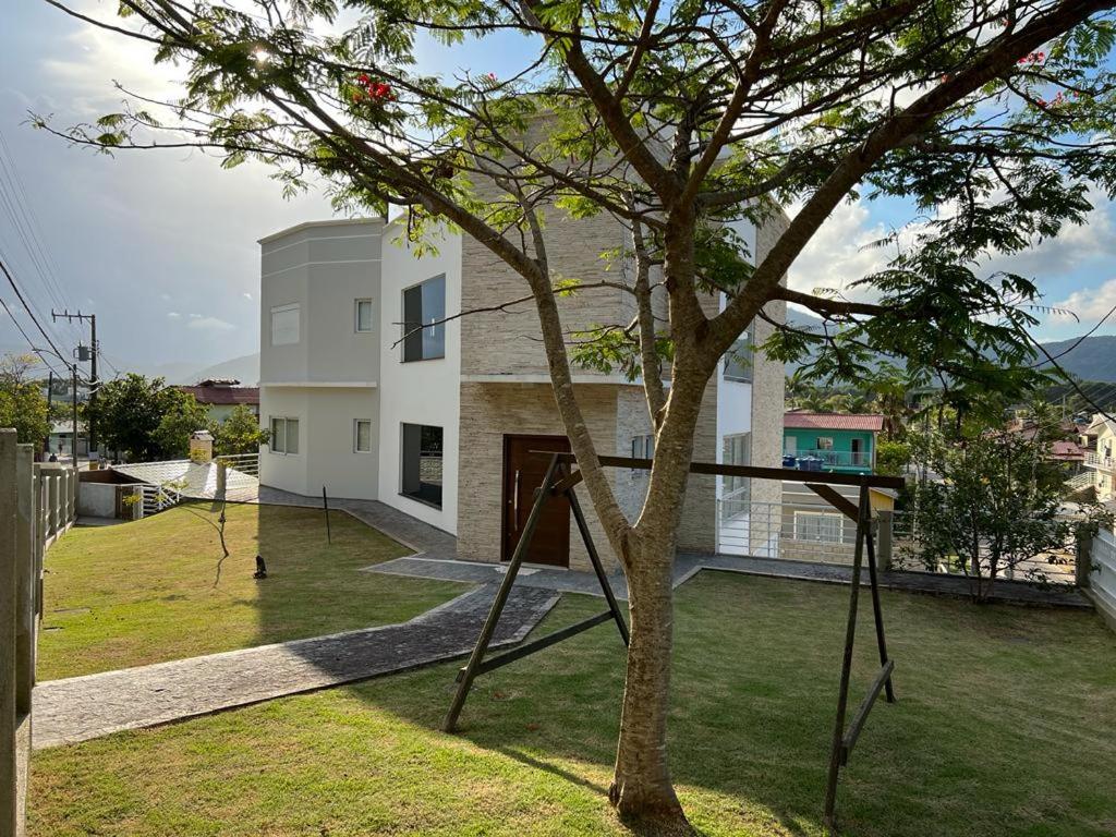 a house with a tree in a yard with swings at Apto 2 in Florianópolis