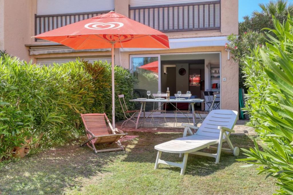 un patio avec deux chaises, une table et un parasol dans l'établissement Magnificent NEWLY renovated close to beach & swimming pool, au Lavandou