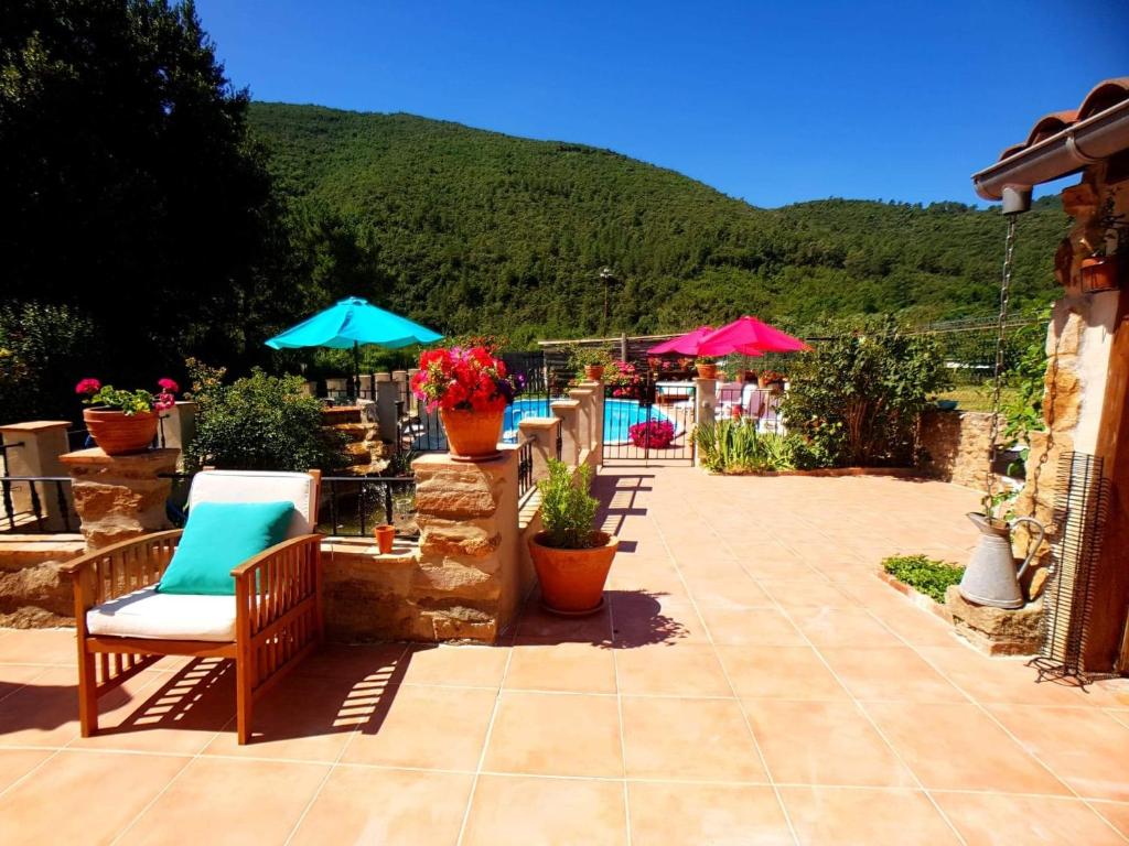 une terrasse avec des chaises et des parasols ainsi qu'une piscine dans l'établissement Le Mas Joyeux - Le Lys - Gite En Cévennes, à Saint-Florent-sur-Auzonnet