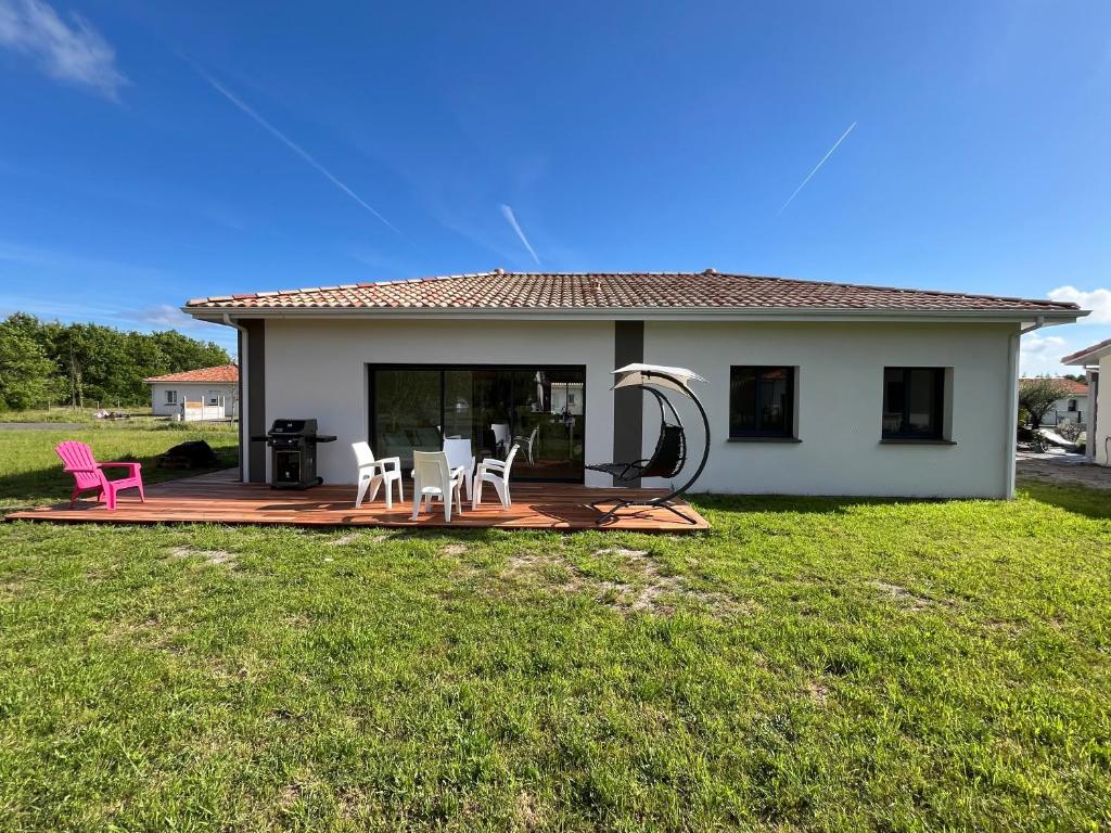 une maison avec une terrasse et deux chaises dans l'établissement Villa Coco 3 chambres, à Parentis-en-Born