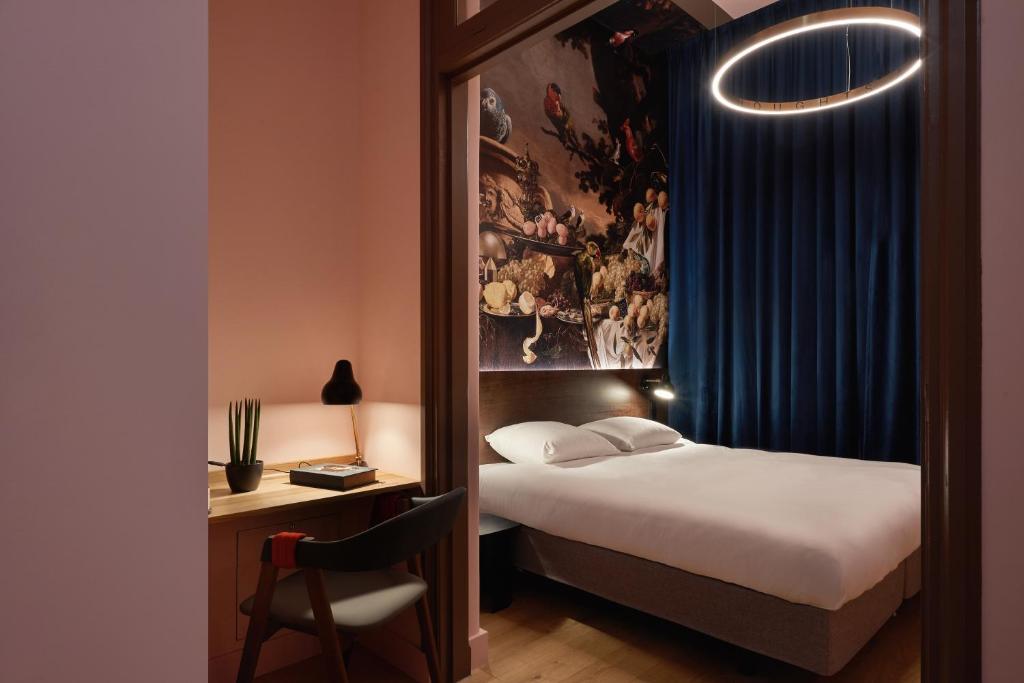 a hotel room with a bed and a desk with a chair at Hotel Mariënhage in Eindhoven