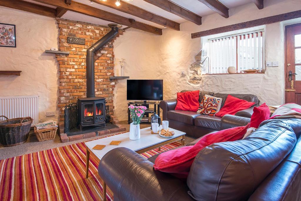 ein Wohnzimmer mit einem Ledersofa und einem Kamin in der Unterkunft Ty Llwyd in Haverfordwest