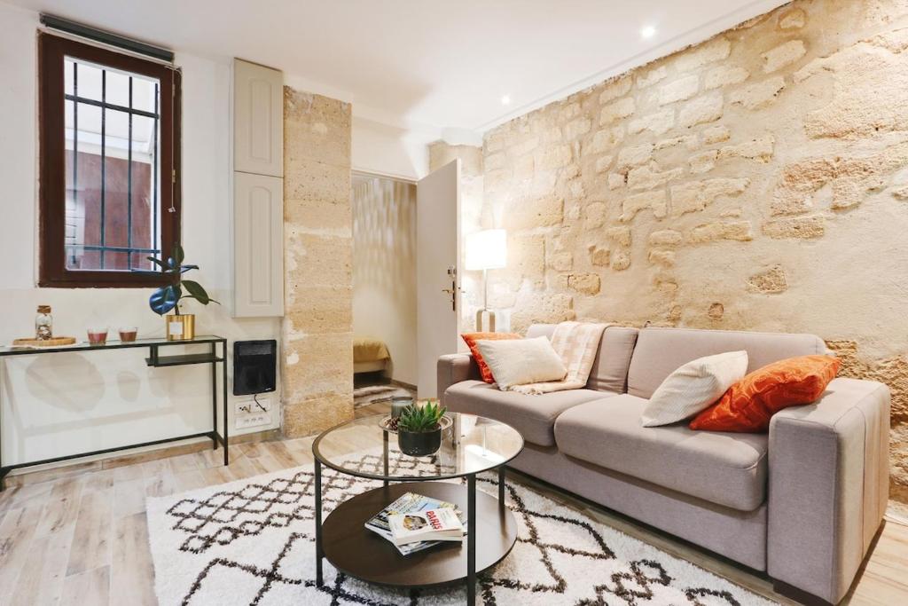 un salon avec un canapé et un mur en pierre dans l'établissement Charmant 2 pièces - Plein Centre de Paris, à Paris