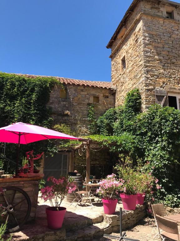une terrasse avec un parasol rose et quelques plantes dans l'établissement Domaine d'Alcapiès, à Saint-Jean-dʼAlcapiès