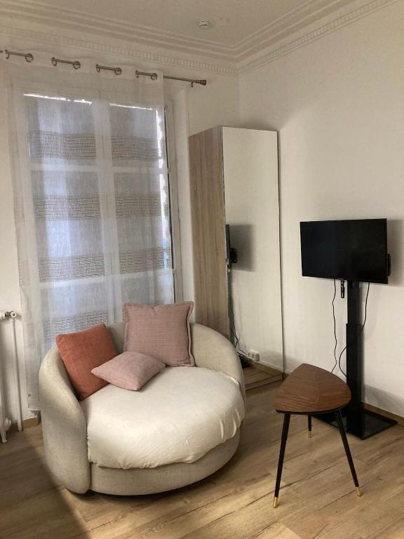 - un salon avec une chaise blanche et des oreillers dans l'établissement Little Home Versailles, à Versailles