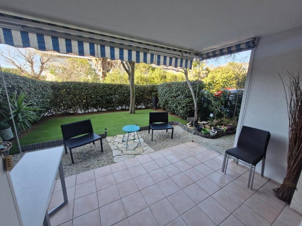 un patio avec deux chaises et une table ainsi qu'un jardin dans l'établissement Le Standing - Fréjus, à Fréjus