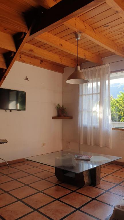 Una sala de estar con una mesa y una ventana. en Simpática y Funcional Cabaña en San Martín, en San Martín de los Andes