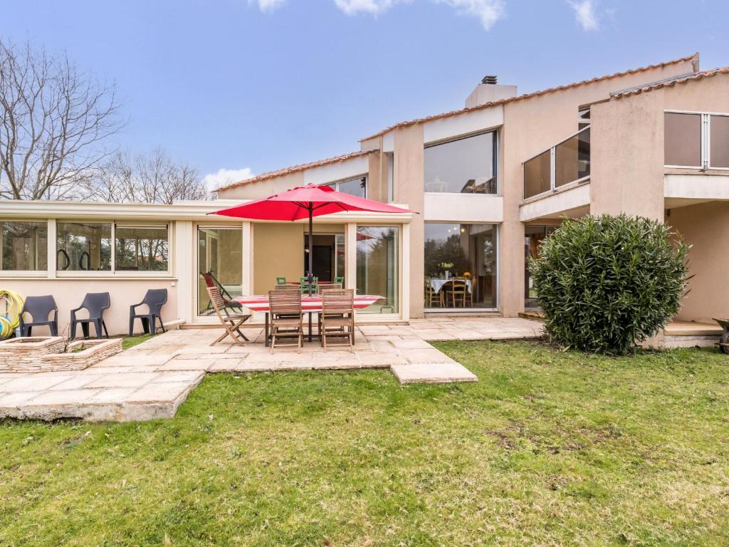 Cette maison dispose d'une terrasse avec une table et un parasol. dans l'établissement Grande maison lumineuse, jardin clos, Wi-Fi inclus - FR-1-306-1295, à Pornic
