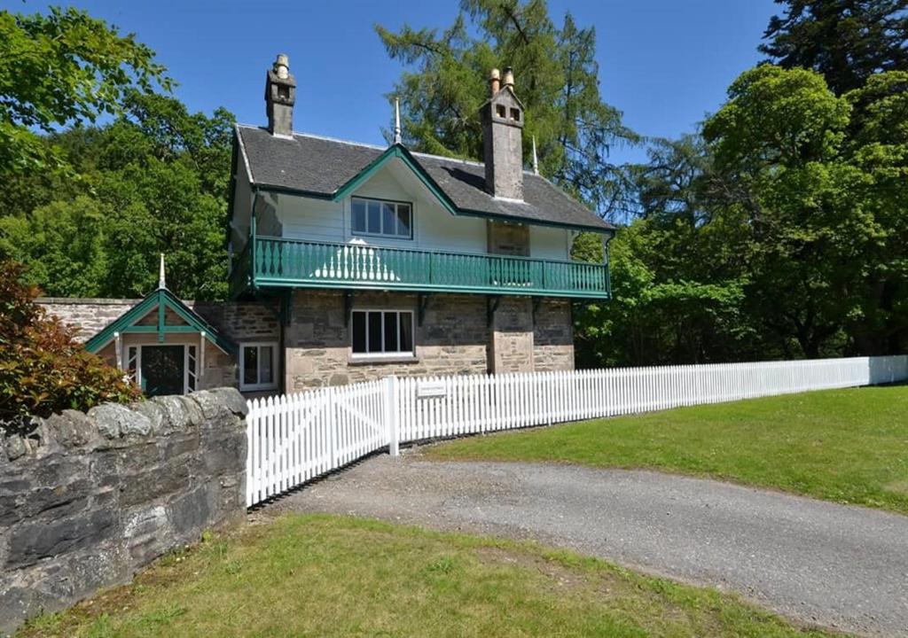 a house with a white fence in front of it at Swiss Cottage in Ballindalloch