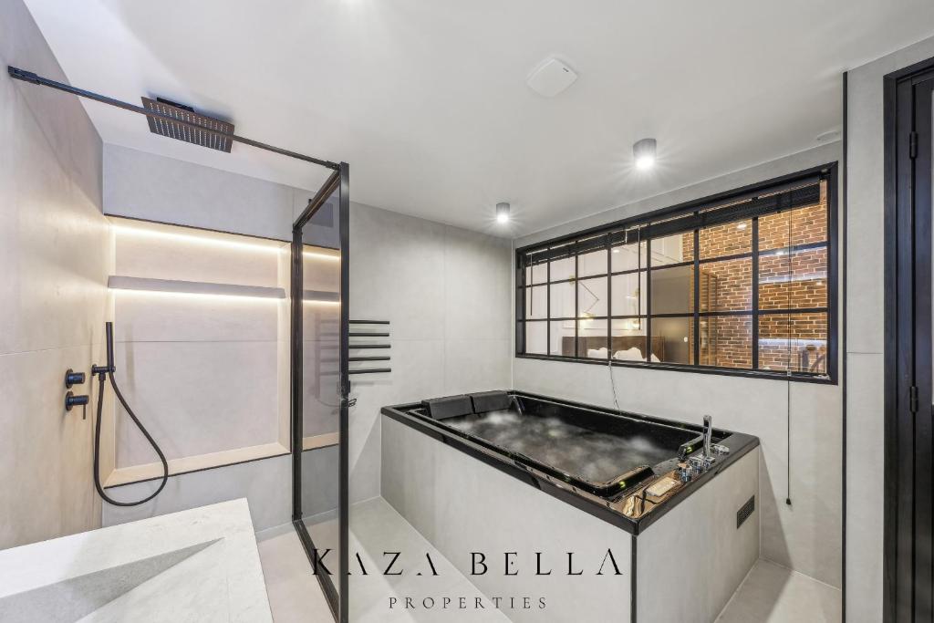 Un baño con bañera y ventana. en KAZA BELLA - Malakoff, en Malakoff