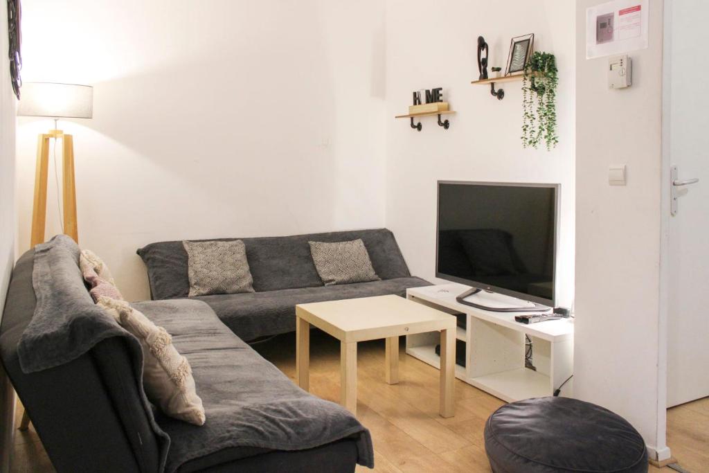 un salon avec un canapé et une télévision dans l'établissement Spacious 69 m nest with balcony, à Aubervilliers
