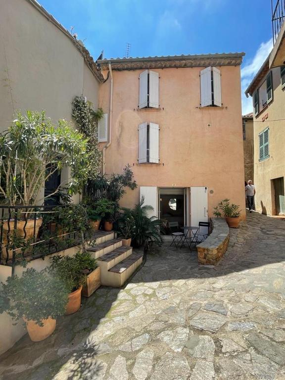 un grand bâtiment avec une cour ornée de plantes en pot dans l'établissement Maison de village 3 chambres avec petite terrasse, à Ramatuelle