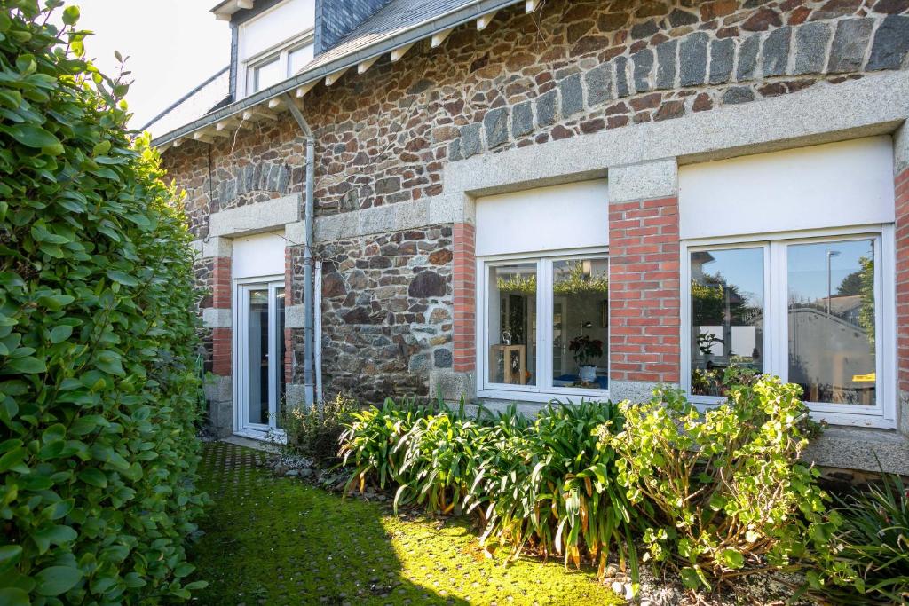 a brick house with windows and plants in the yard at Maison du pêcheur 150 m plages in Saint-Quay-Portrieux