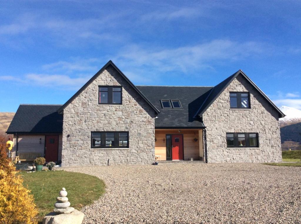 a large stone house with a red door at Ceo Mara Croft in Taynuilt