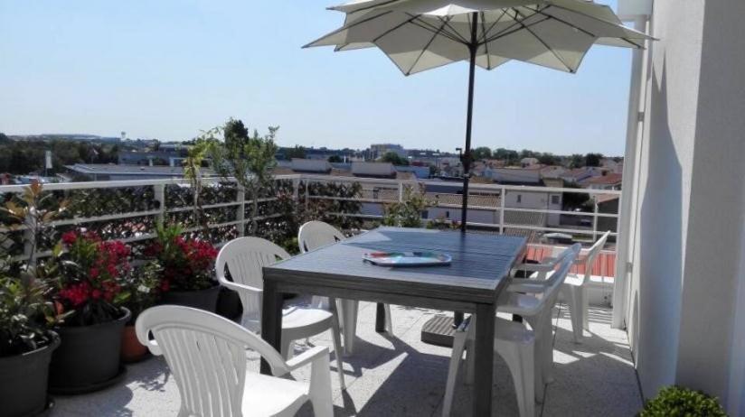 une table et des chaises sur un balcon avec un parasol dans l'établissement Appt 3 pièces LA ROCHELLE - LR360-307, à La Rochelle