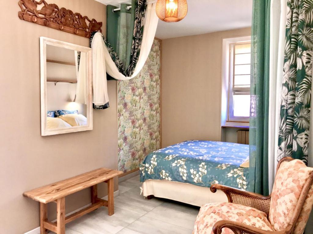 une chambre avec un lit, une chaise et un miroir dans l'établissement Chambre Funky - Gîte les Zazous, à Lormes