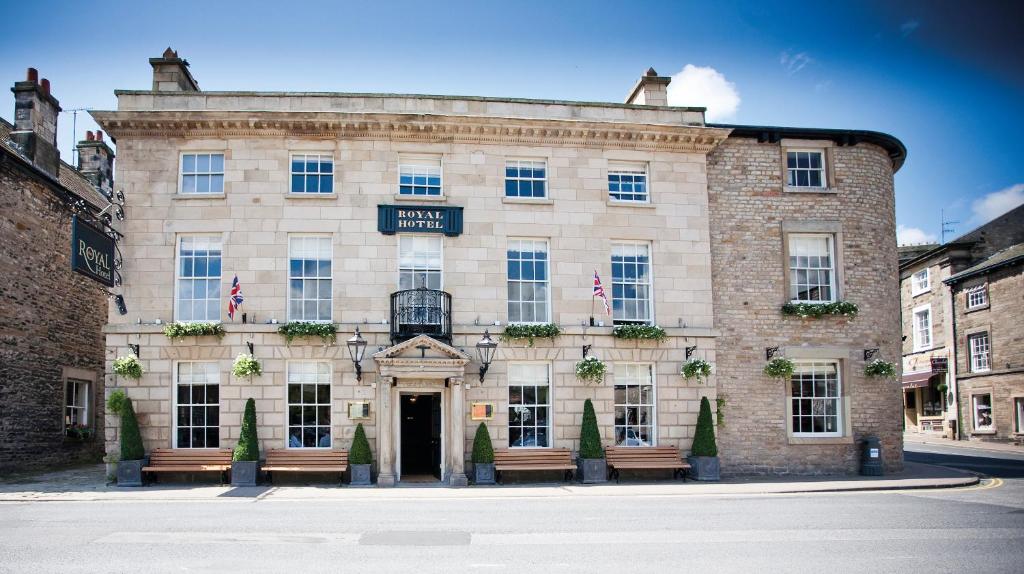 a large brick building with benches in front of it at The Royal Hotel in Kirkby Lonsdale