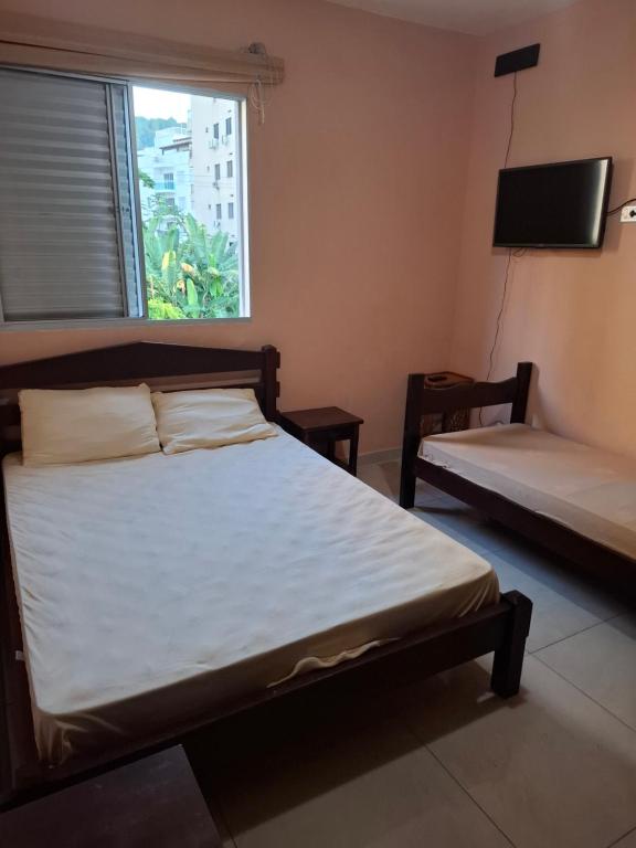 a bedroom with two beds and a large window at Apartamento Praia Guarujá in Guarujá