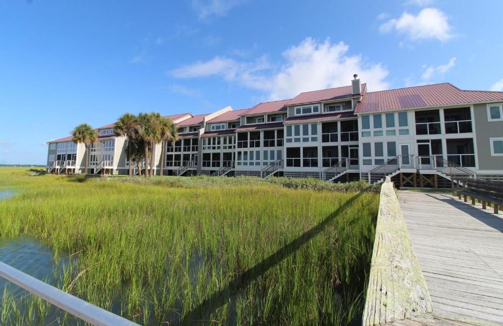 a resort with a boardwalk and tall grass at Surf and Turf in Folly Beach