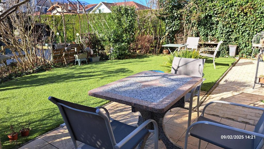 a table and chairs in a yard with a lawn at T2 de 55m avec jardin et parking privatifs in Aix-les-Bains