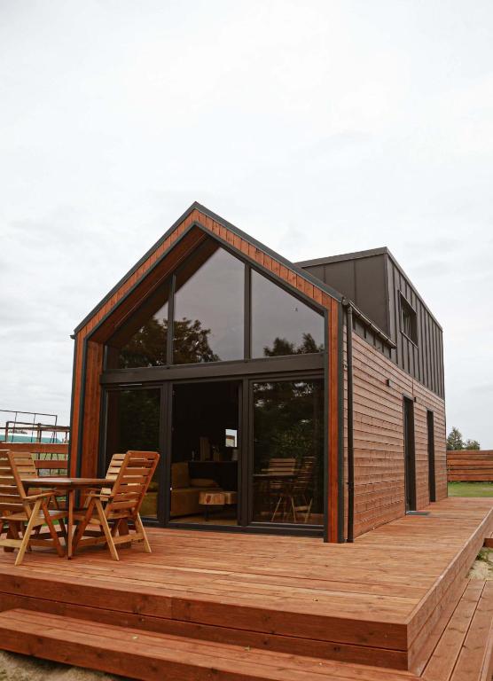 a house with glass doors and a wooden deck at Black & White Cekcyn Bory Tucholskie in Cekcyn