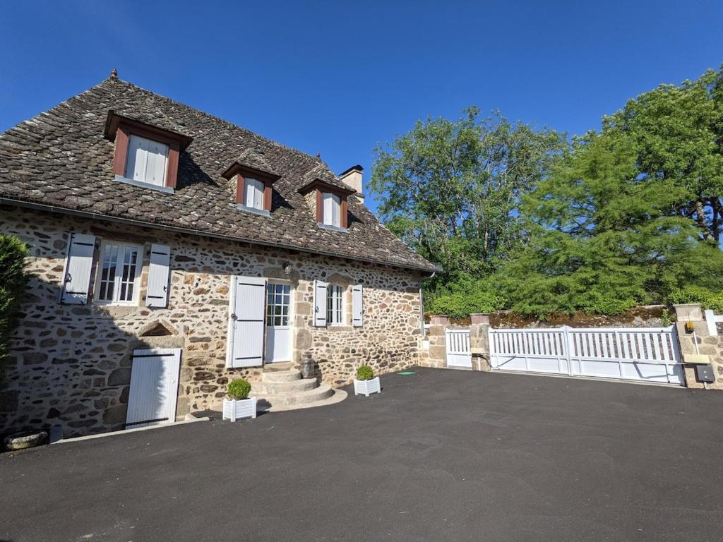 une maison en pierre avec une clôture blanche et une allée. dans l'établissement Typical Cantal house in Montvert, à Montvert