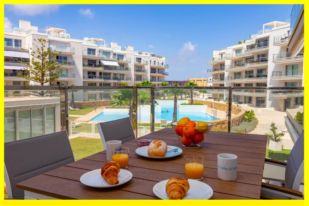 a table with plates of food and orange juice on a balcony at Denia Apartment Marina Real in Denia