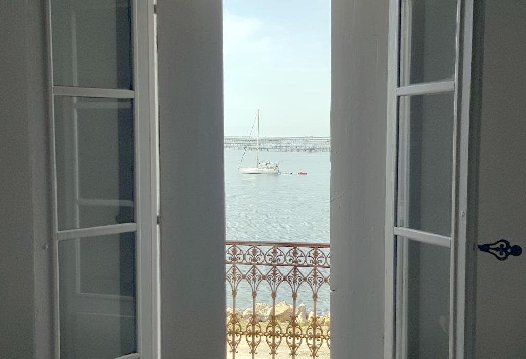 une fenêtre avec vue sur un bateau dans l'eau dans l'établissement La petite Maison, à Bouzigues