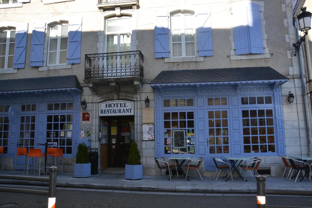 een gebouw met een tafel en stoelen ervoor bij Logis Hôtel de France in Arudy