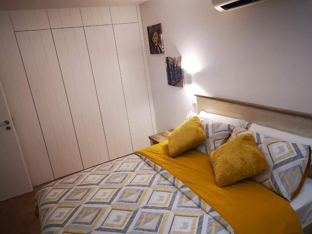 een slaapkamer met een bed met gele lakens en kussens bij Casa da Vila in Ferragudo