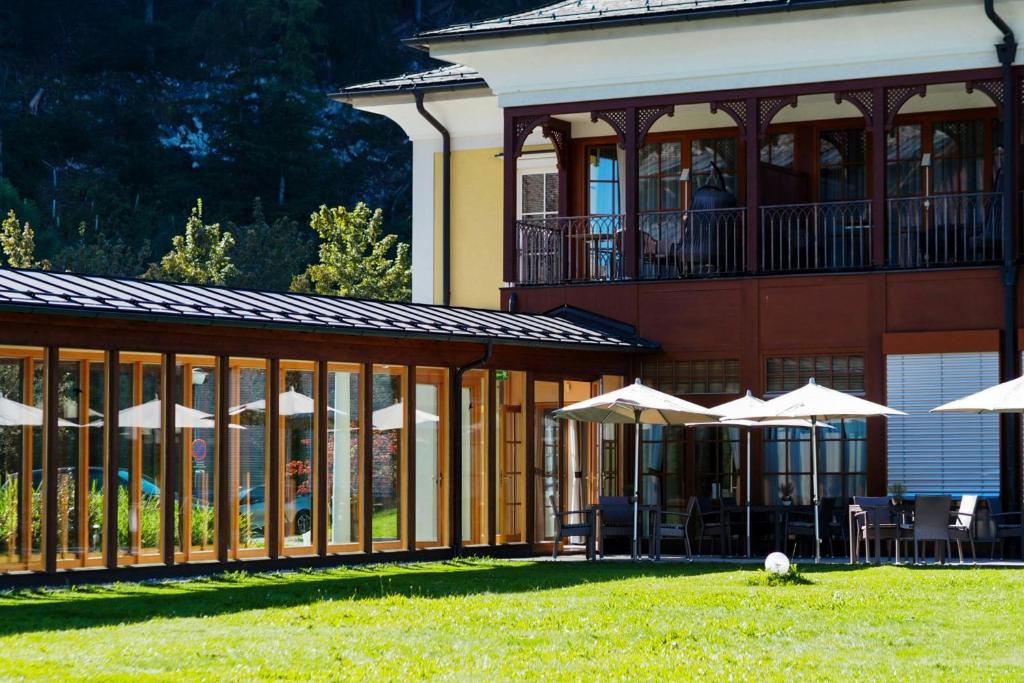 a building with tables and umbrellas in front of it at Arabella Jagdhof Resort am Fuschlsee, a Tribute Portfolio Hotel in Hof bei Salzburg