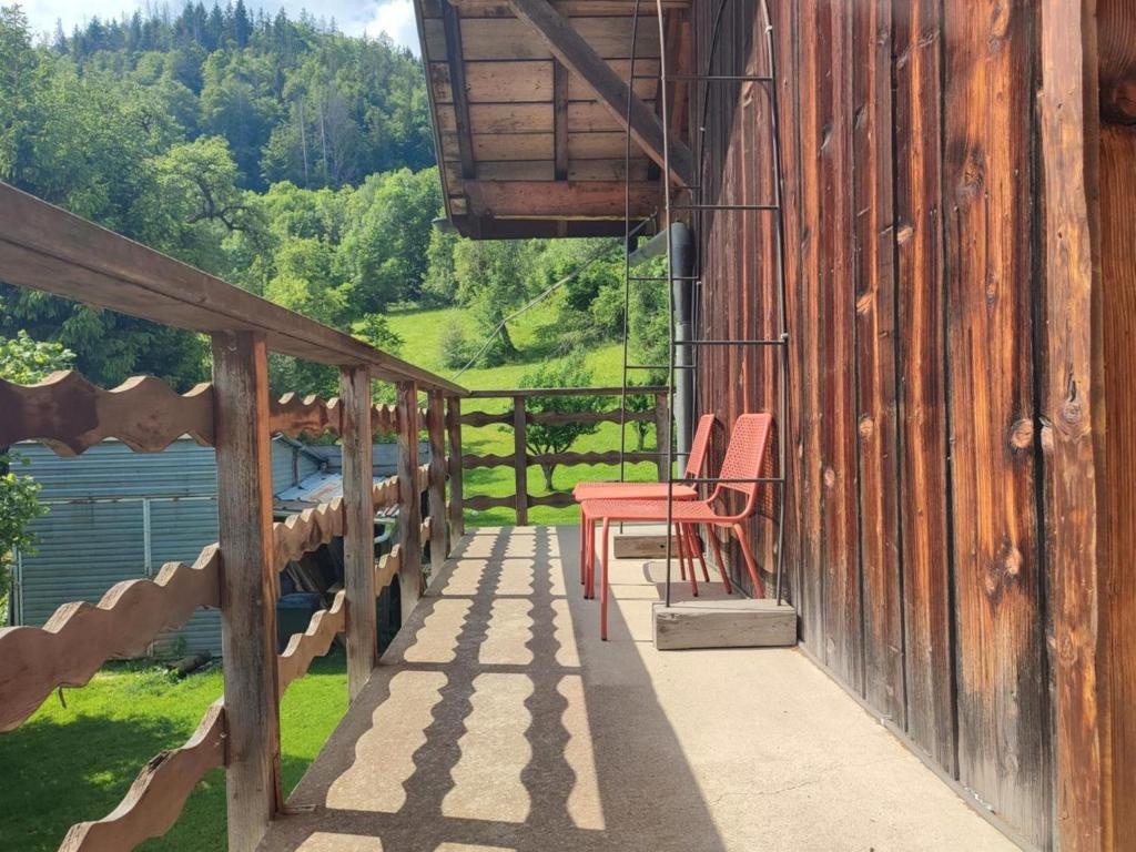 une terrasse couverte en bois avec une chaise rouge sur le côté du bâtiment dans l'établissement Accotinae, à Mont-Saxonnex