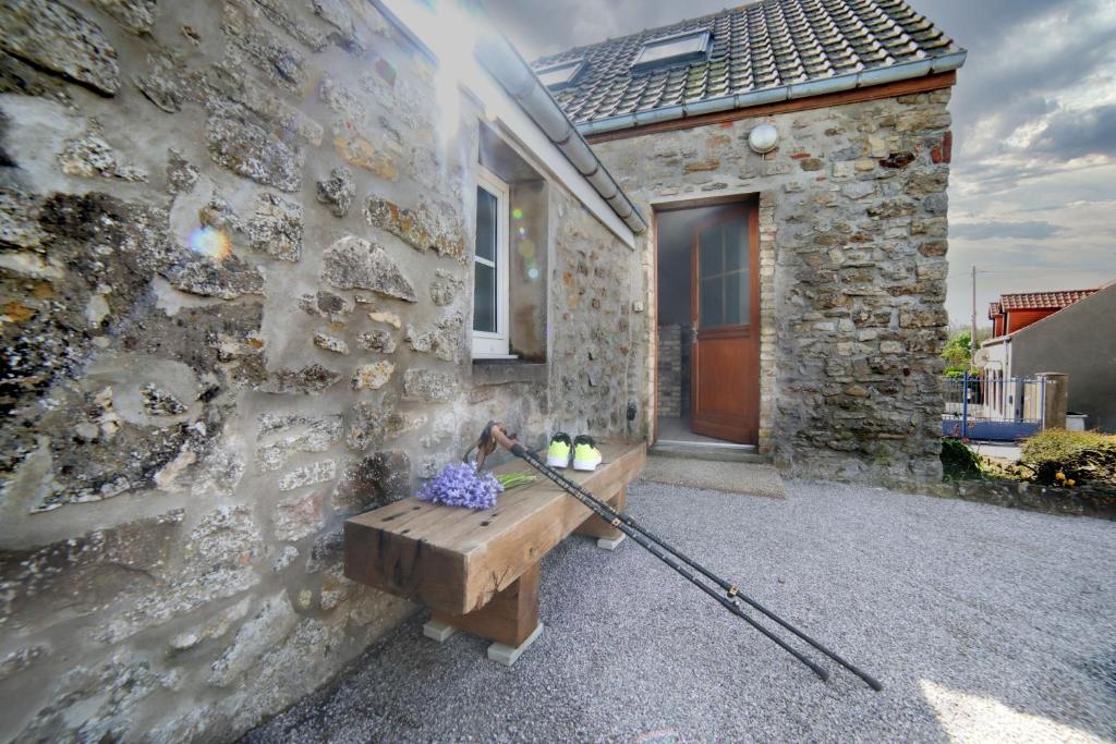 - un bâtiment en pierre avec un banc en bois et une batte de baseball dans l'établissement Gîte de la Créche, à Wimereux