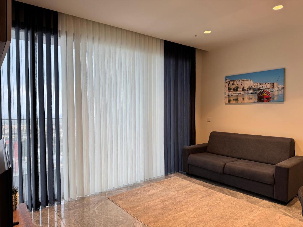 a living room with a couch and a large window at Sea view Mercury Tower, Rooftop infinity Pool in St. Julianʼs