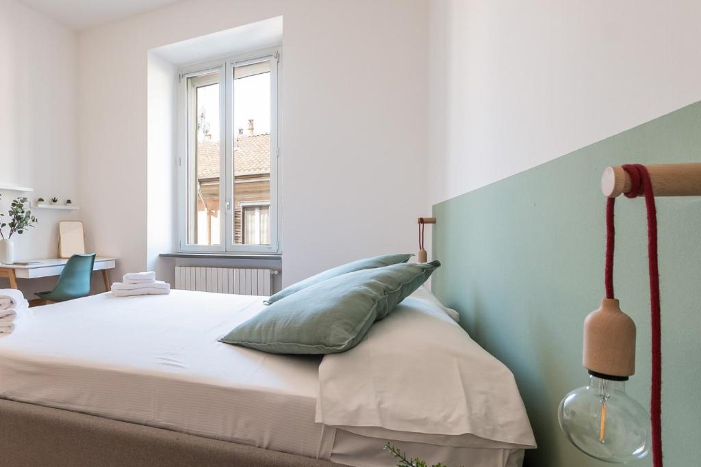 Un dormitorio con una cama con almohadas verdes y blancas. en Bocconi District Suite - Bocconi Navigli - Milan-Cortina 2026 Olympics - Milan Design Week 2026, en Milán
