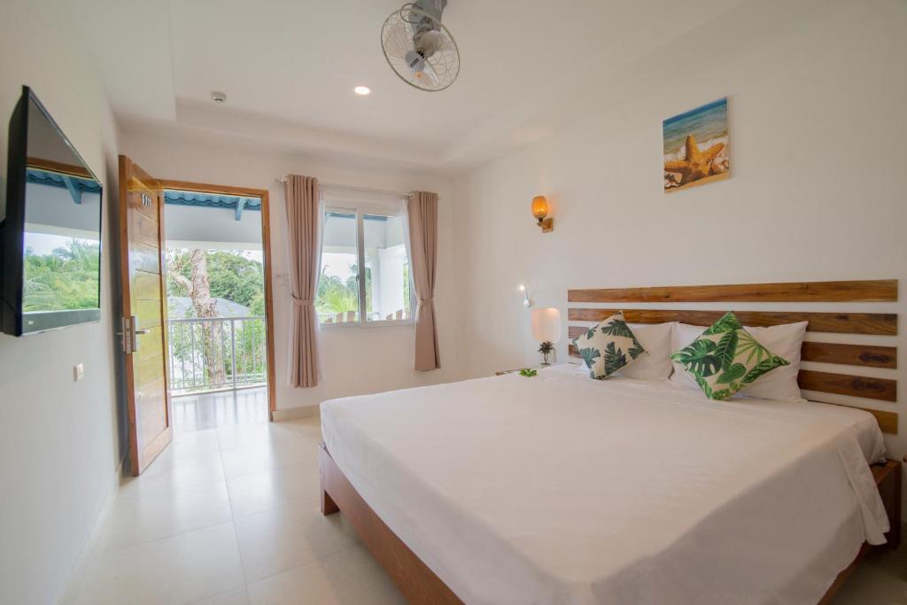 a white bedroom with a large bed and a window at Palma Resort in Phu Quoc