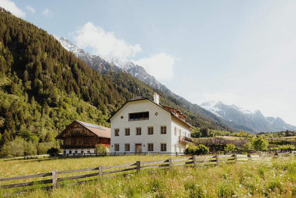 a white house in a field with mountains in the background at Halbwöhrerhof in Anterselva di Mezzo