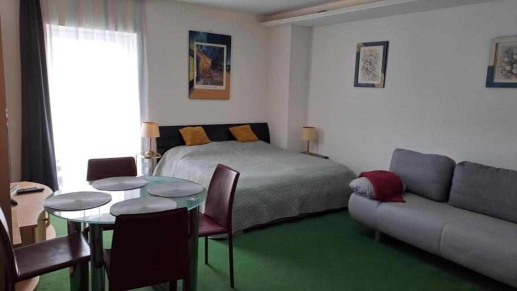 ein Schlafzimmer mit einem Bett, einem Tisch und einer Couch in der Unterkunft Central City 2 Apartman in Debrecen