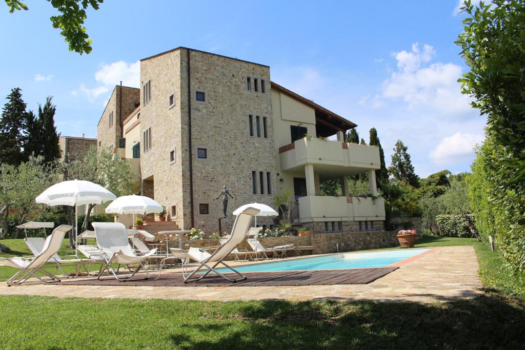 um grupo de cadeiras e guarda-sóis em frente a um edifício em La Compagnia del Chianti em San Donato in Poggio