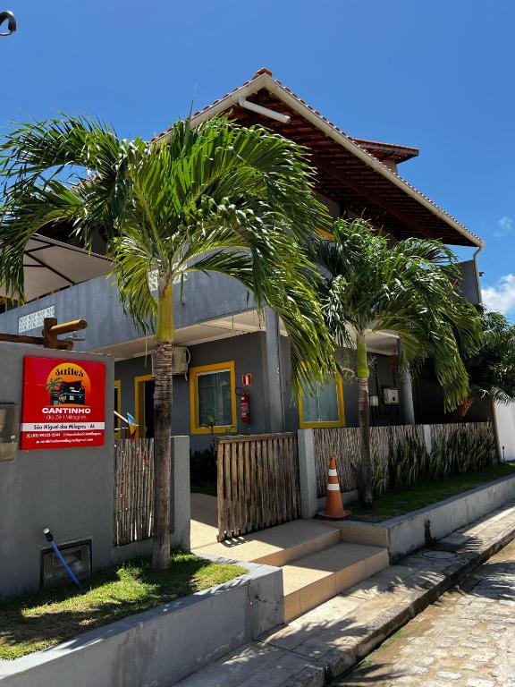 a house with a palm tree in front of it at Suítes Cantinho do Ze em Milagres in São Miguel dos Milagres