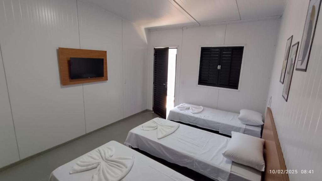 a room with three beds and a tv in it at Inocência Park Hotel in Inocência