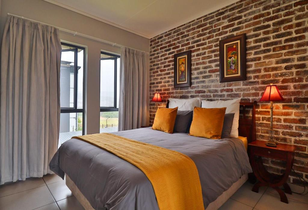 une chambre avec un grand lit avec un mur de briques dans l'établissement Luxury Lowveld Apartment, à Nelspruit