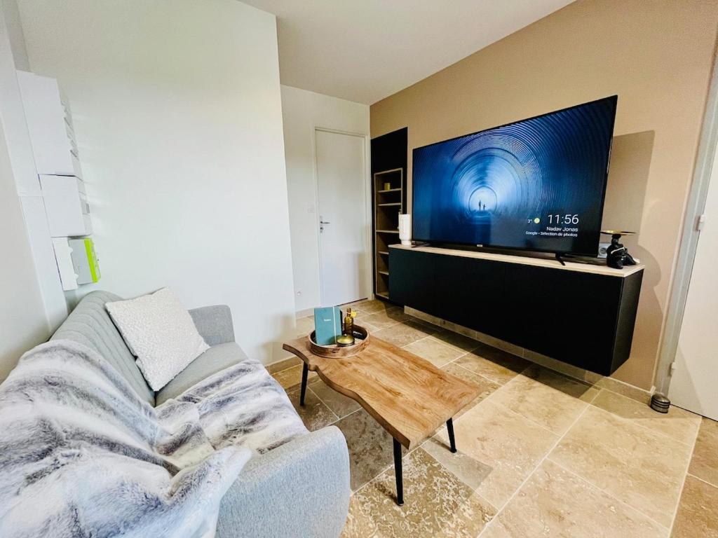 un salon avec un canapé et une télévision à écran plat dans l'établissement Repos Cosy à Bourgoin avec Parking privatif, à Bourgoin-Jallieu
