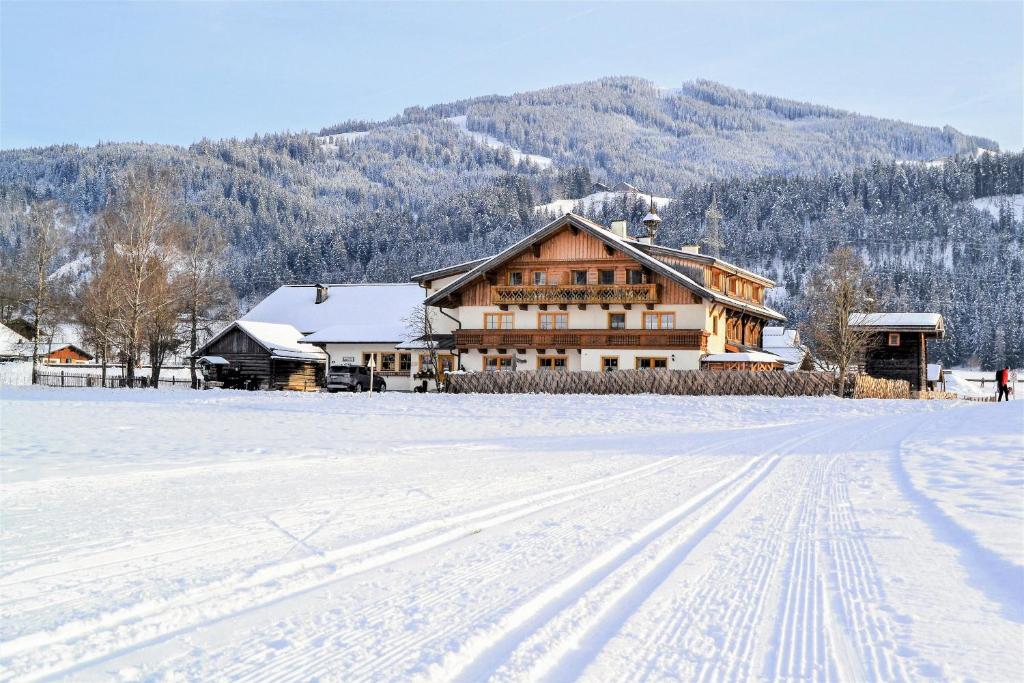 a snow covered field with a house in the background at Appartement Arnoldgut in Altenmarkt im Pongau