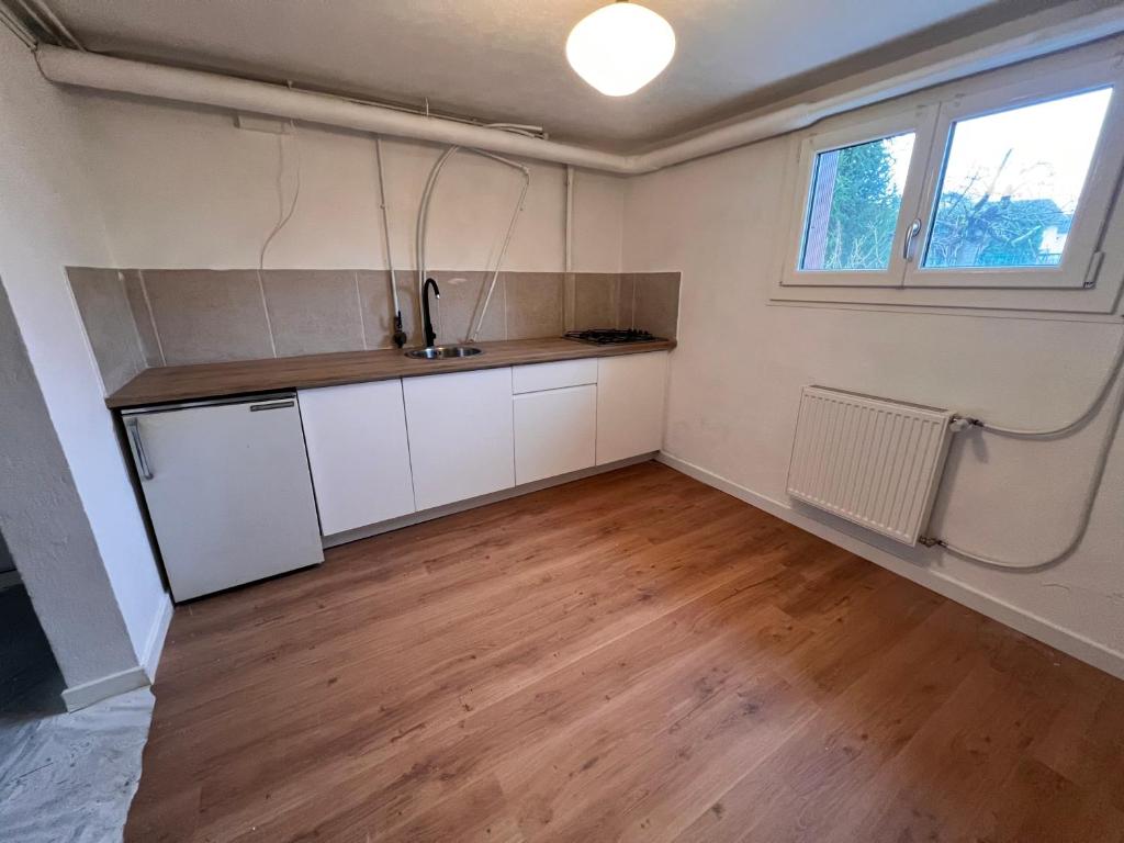 une cuisine avec des armoires blanches et un plancher en bois dans l'établissement Au petit prince, à Dole